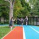 A young girl off to the sideline as a group of girls are running on a track