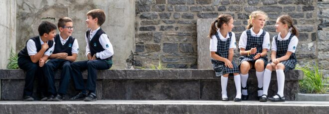 Three boys sitting sitting to the left and three girls sitting to the right on stone steps