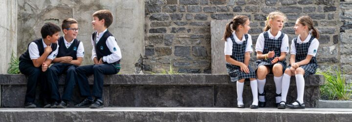 Three boys sitting sitting to the left and three girls sitting to the right on stone steps