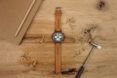 A brown watch against a wood background.