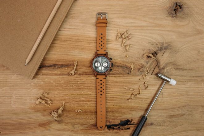 A brown watch against a wood background.