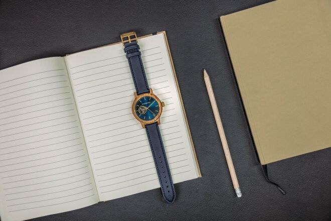 A bleu watch laid against a notebook.