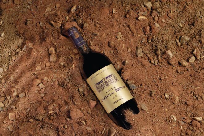 A bottle that reads Cantenac Brown buried in dirt