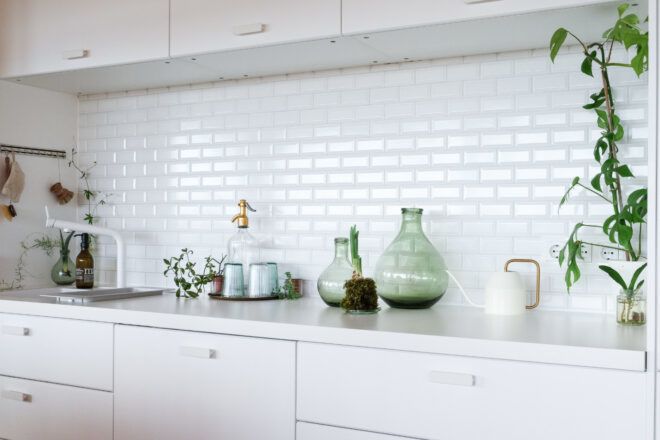 Kitchen counter with plants and kitchen tools in front of a white backsplash