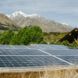 View of the photovoltaic panels in the solar garden surrounded by vegetation and mountains at the back