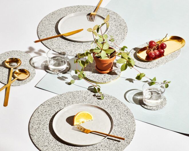 A spread of plates on top of circular place mats and clear glass cups on top of grey coasters