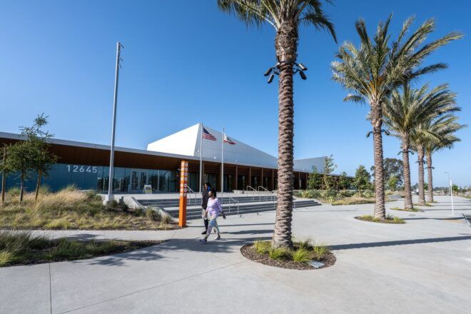 A long building with palm tress that are planted in front of it