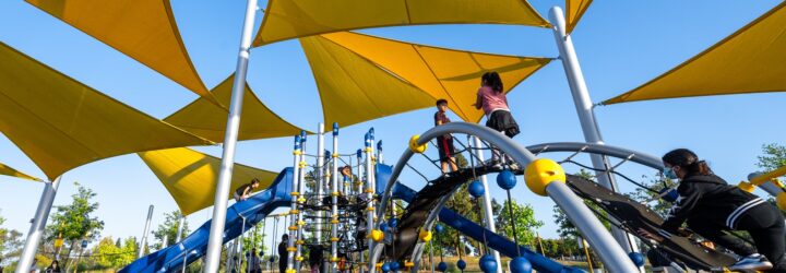 A playground that is covered by yellow triangle overhangs