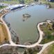 An aerial view of the park has a large lake with walking trails surrounding it