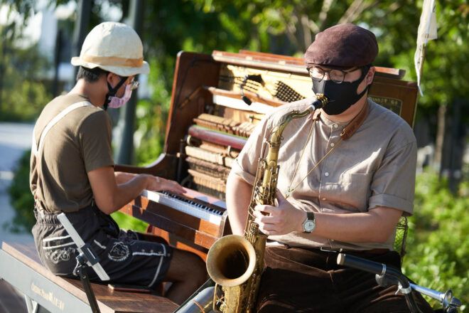 A person playing piano sitting next to a person playing saxophone.