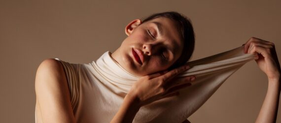 A woman with her eyes closed stretching out the collar of her top away from her