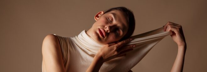 A woman with her eyes closed stretching out the collar of her top away from her