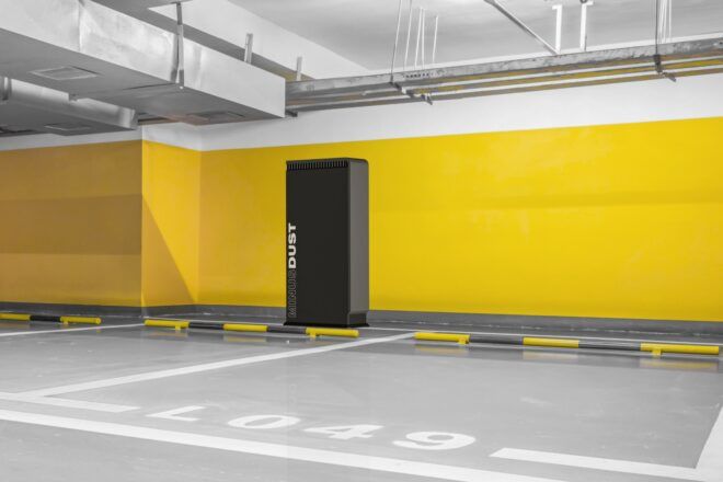 A large rectangle box sits in an indoor parking structure that has yellow painted walls