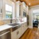 A kitchen with white countertops and stainless steal dishwasher and sink with wooden floors