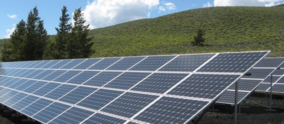 A row of solar panels in a green hill area