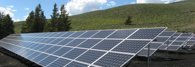 A row of solar panels in a green hill area