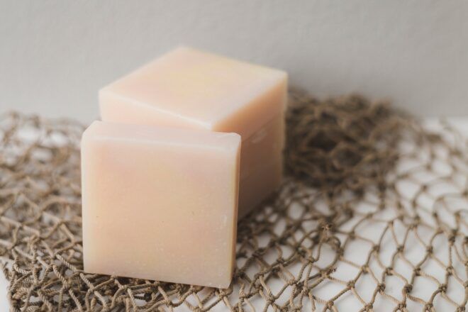 Two cubes of peach-colored soap sitting on a mesh material
