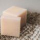 Two cubes of peach-colored soap sitting on a mesh material