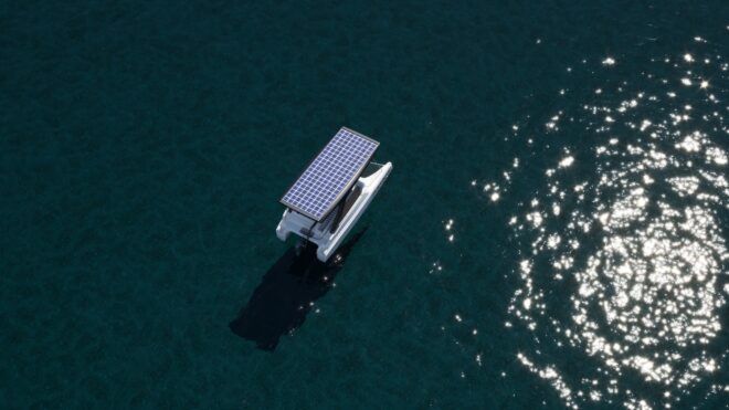 A solar powered catamaran shot from up top floating in sea of water