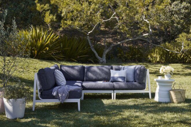A grey sofa sitting in a grass area
