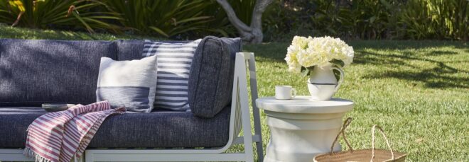 A portion of a grey sofa with pillows on it and a decorative white sculpture next to it