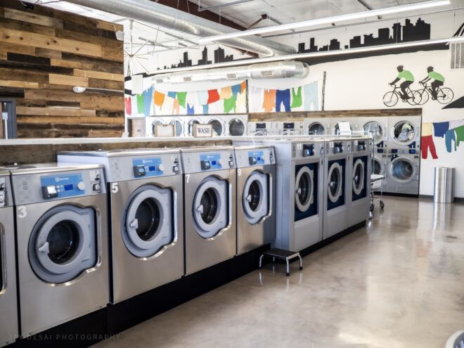 Laundry machines in a laundromat with murals painted on the walls