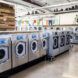 Laundry machines in a laundromat with murals painted on the walls