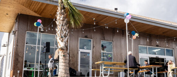Exterior view of the Green Laundry Lounge with a few people sitting on the picnic tables outside
