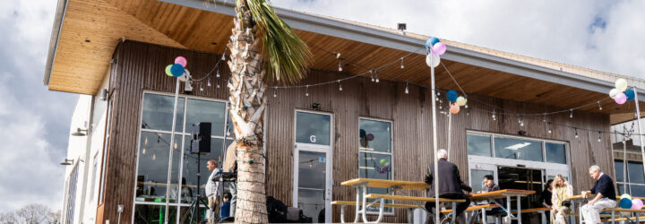 Exterior view of the Green Laundry Lounge with a few people sitting on the picnic tables outside