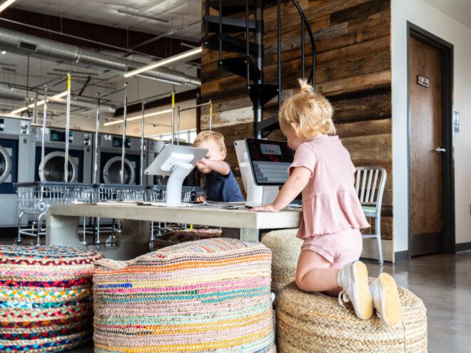 Two children sitting on recycled-material bean bag stools using iPads