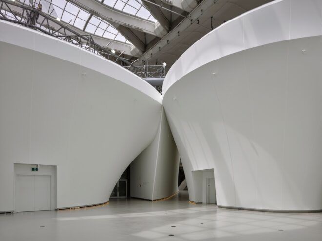 Two white buildings encased underneath a glass ceiling