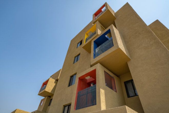 View from the ground level of a yellow ochre building with colorful cube-shaped apartments
