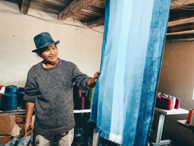 A man wearing a blue hat holding a blue draped cloth that hangs from the ceiling
