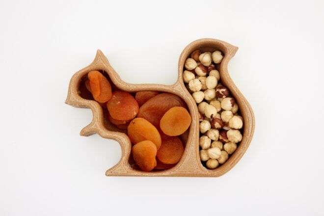 A container shaped like a squirrel with its body filled with dried fruits and its tail filled with dried nuts