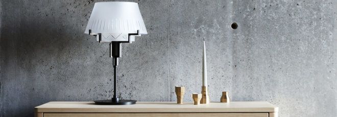 A lamp and candlesticks atop a dresser.