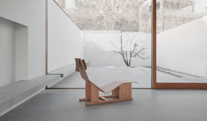 A wooden chaise lounge chair in a minimalistic room