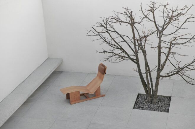 A wooden chaise lounge in a minimalistic courtyard