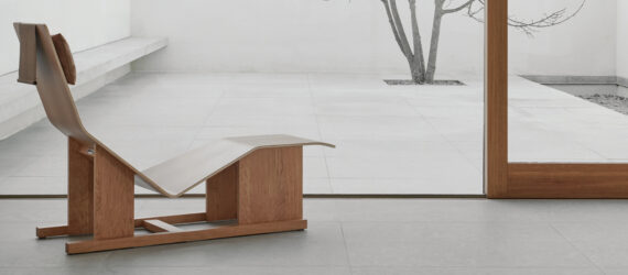 A wooden chaise lounge facing a large window