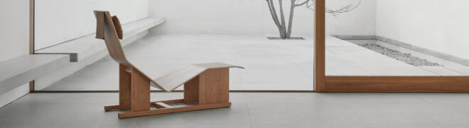 A wooden chaise lounge facing a large window