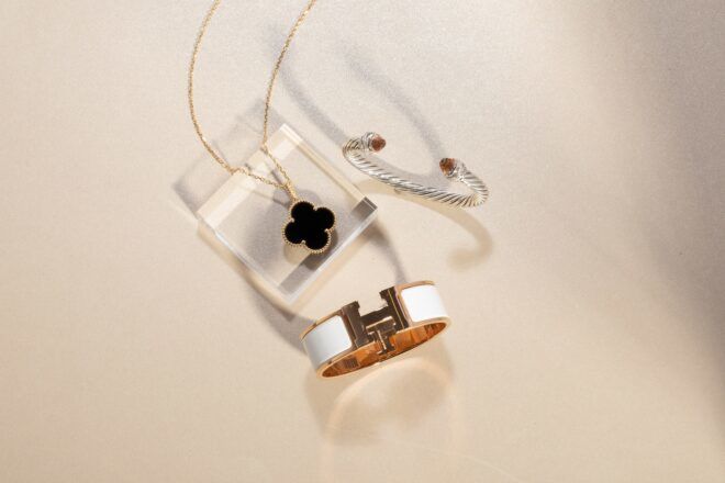 A simple black clover pendant necklace with a gold chain, a white cuff bracelet and a diamond bracelet