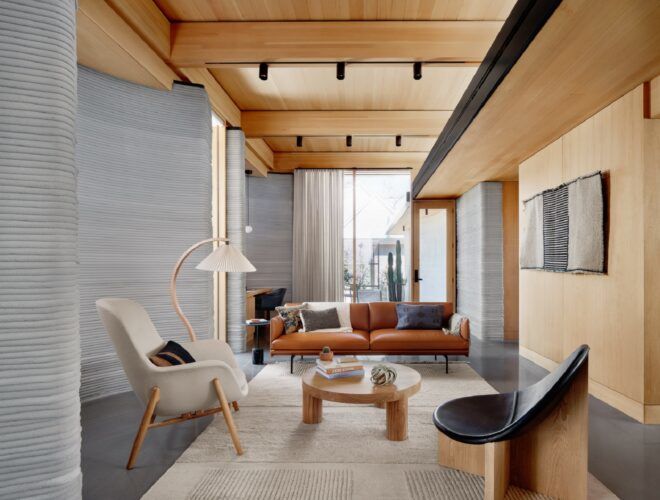 A living room area with a red couch, a white chair and a small wooden coffee table