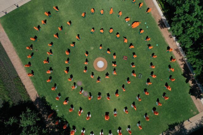 Orange 3D printed statues of women arranged in a spiral