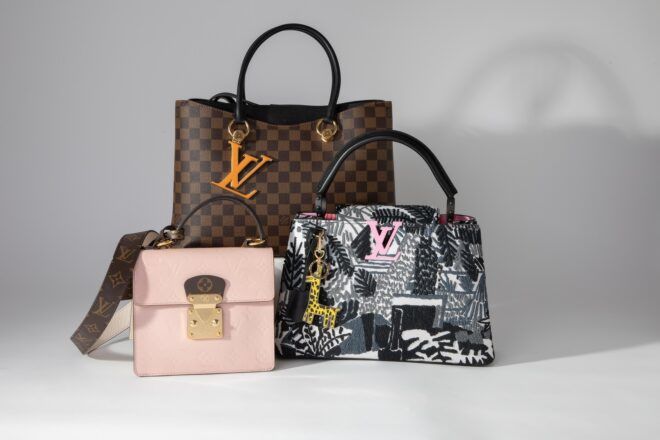 Three purses set against a white backdrop. In the front is a tiny pink purse and a medium-sized grey purse. Behind them is a large brown purse