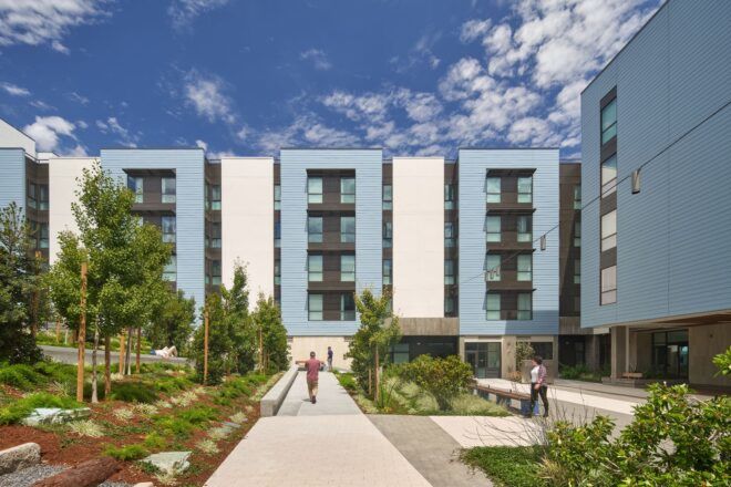 A blue apartment complex with a courtyard in front of it