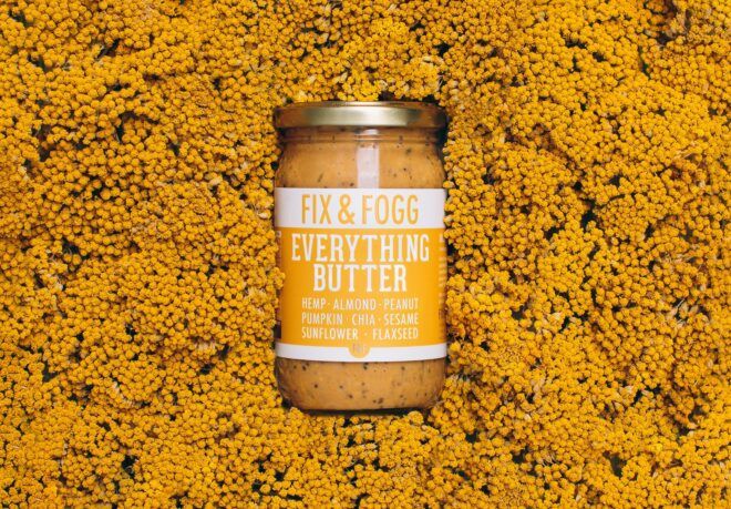 A jar of Fix and Fogg nut butter surrounded by yellow flowers