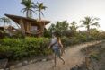 A person walking on a sandy path by a bamboo structure.