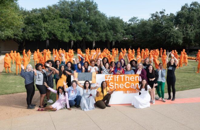 A group of women holding a sign that read #IfThenSheCan in front of orange 3D printed sculptures