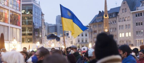 A crowd of people next to a raise Ukraine flag.