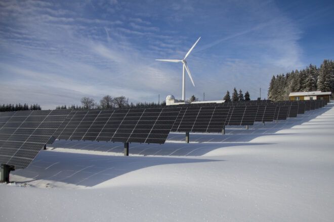 Solar panels in front of a windmill.