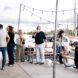 People gathered in the patio space at the front of Green Laundry Lounge. Some are seated at the picnic tables and others are standing near the entrance